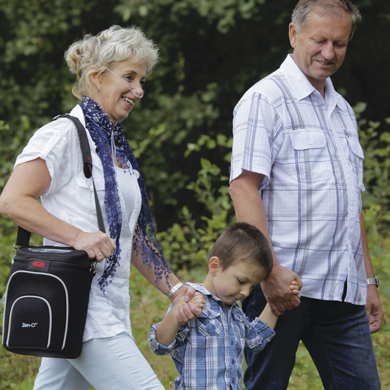 Woman with Zen-O-Lite portable oxygen device walking with family